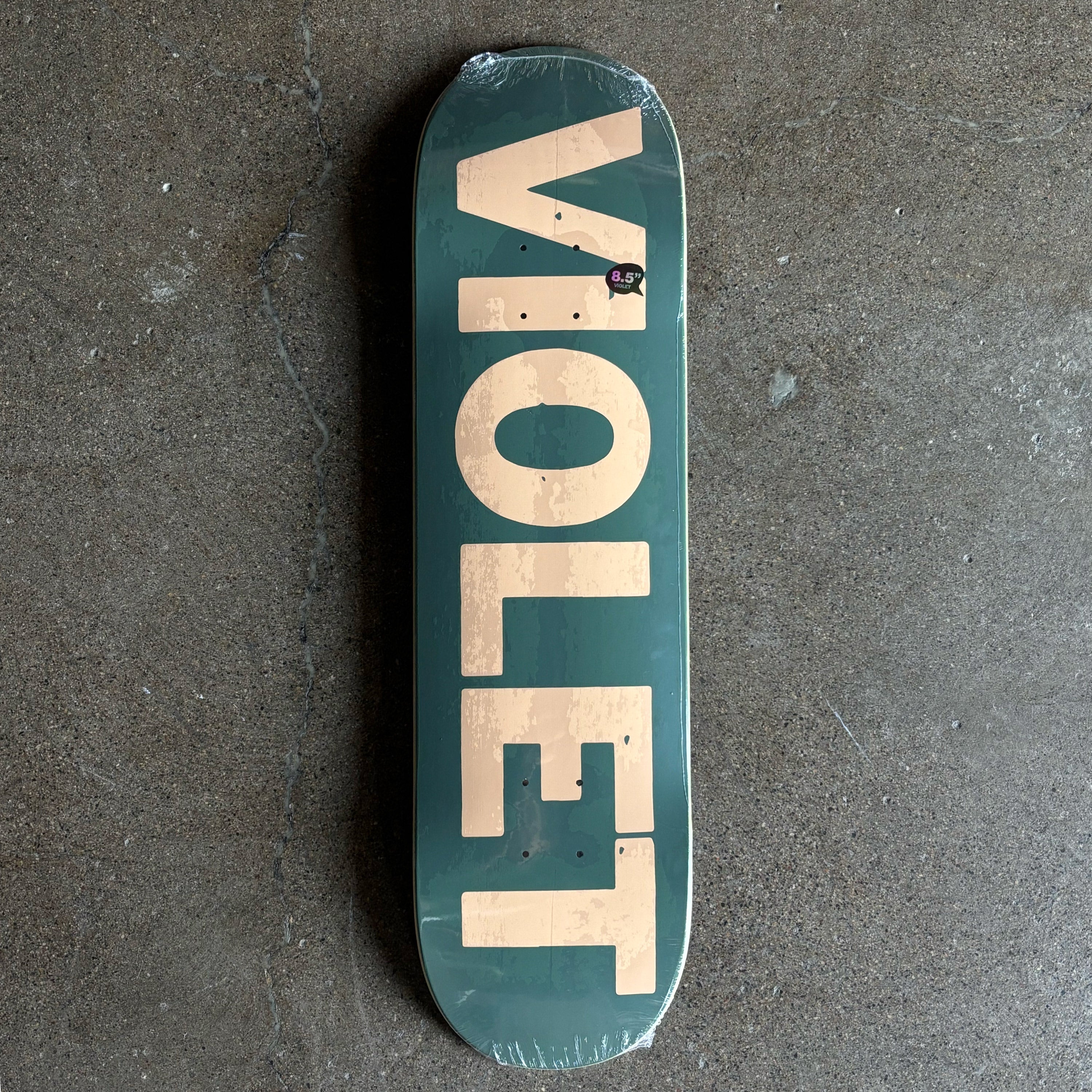 Full image of skateboard deck. Olive green with Violet logo in cream.